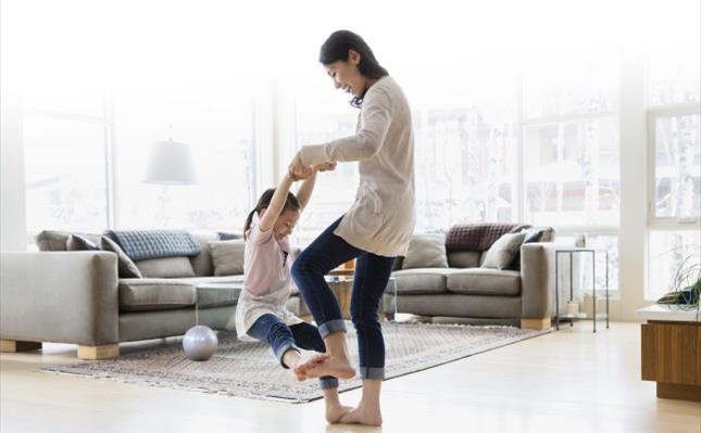 Mother and daughter dancing in living room