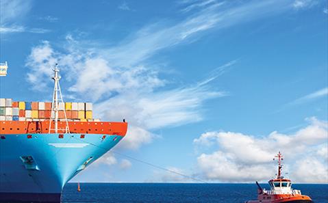 Tugboat towing a large container ship at sea