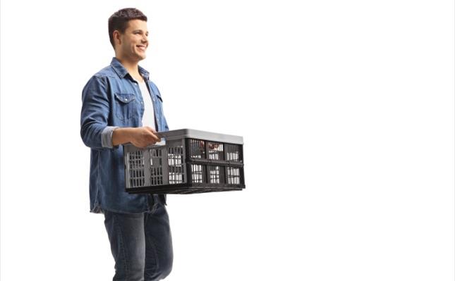 Young guy walking and holding a plastic crate