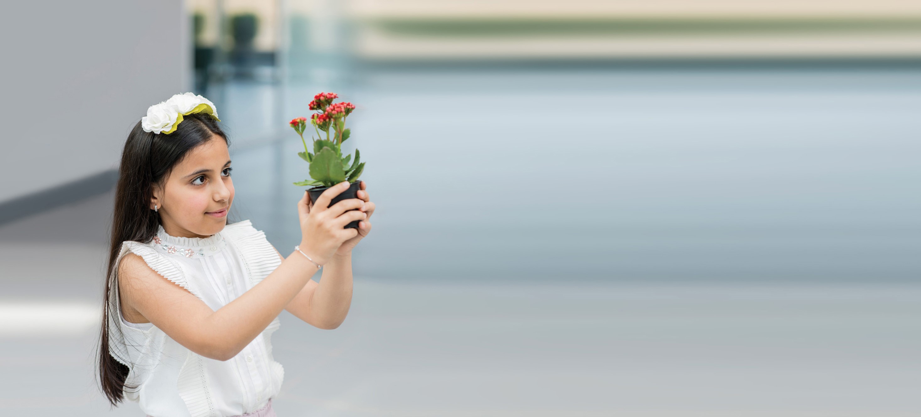 Young girl holding a pot with a red flower