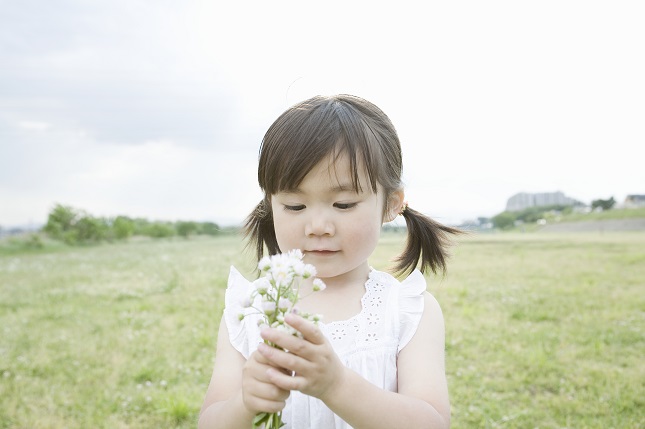 girl standing in a field holding flower