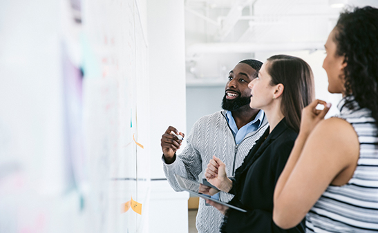 Three people looking at a whiteboard Three people looking at a whiteboard